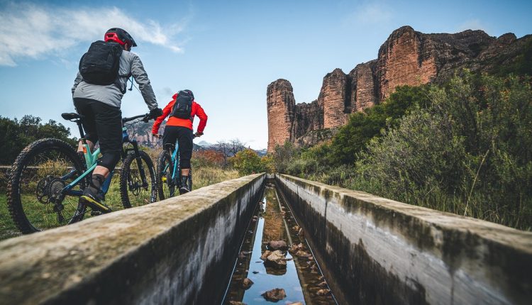 Dos 'biker' en dirección a Riglos con los emblemáticos Mallos al fondo de la imagen. Foto: Nacho Trueba